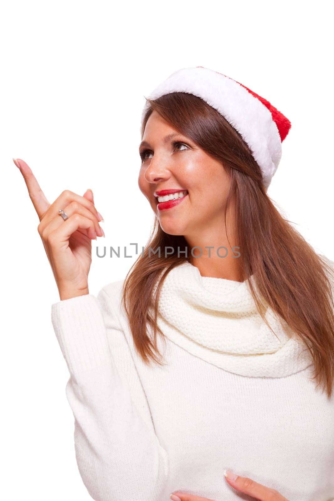 Young attractive woman with red Christmas hat points her finger in one direction isolated on white background
