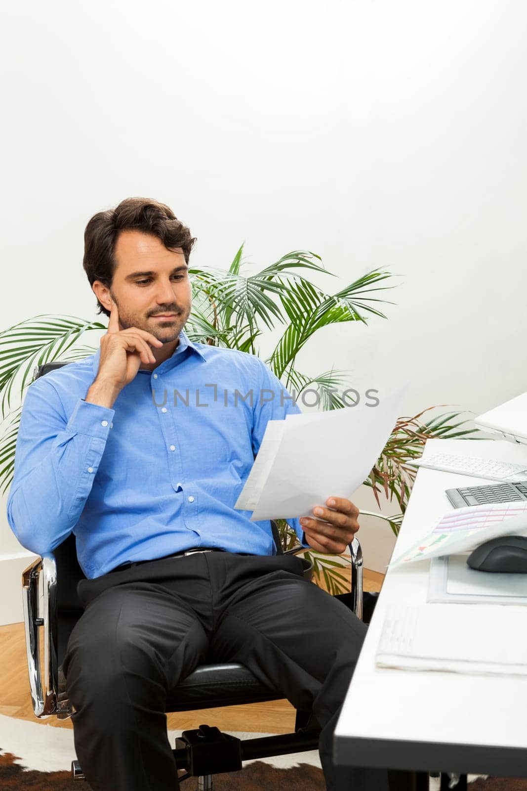 Young businessman sits with documents at a grater table in the office and informs himself