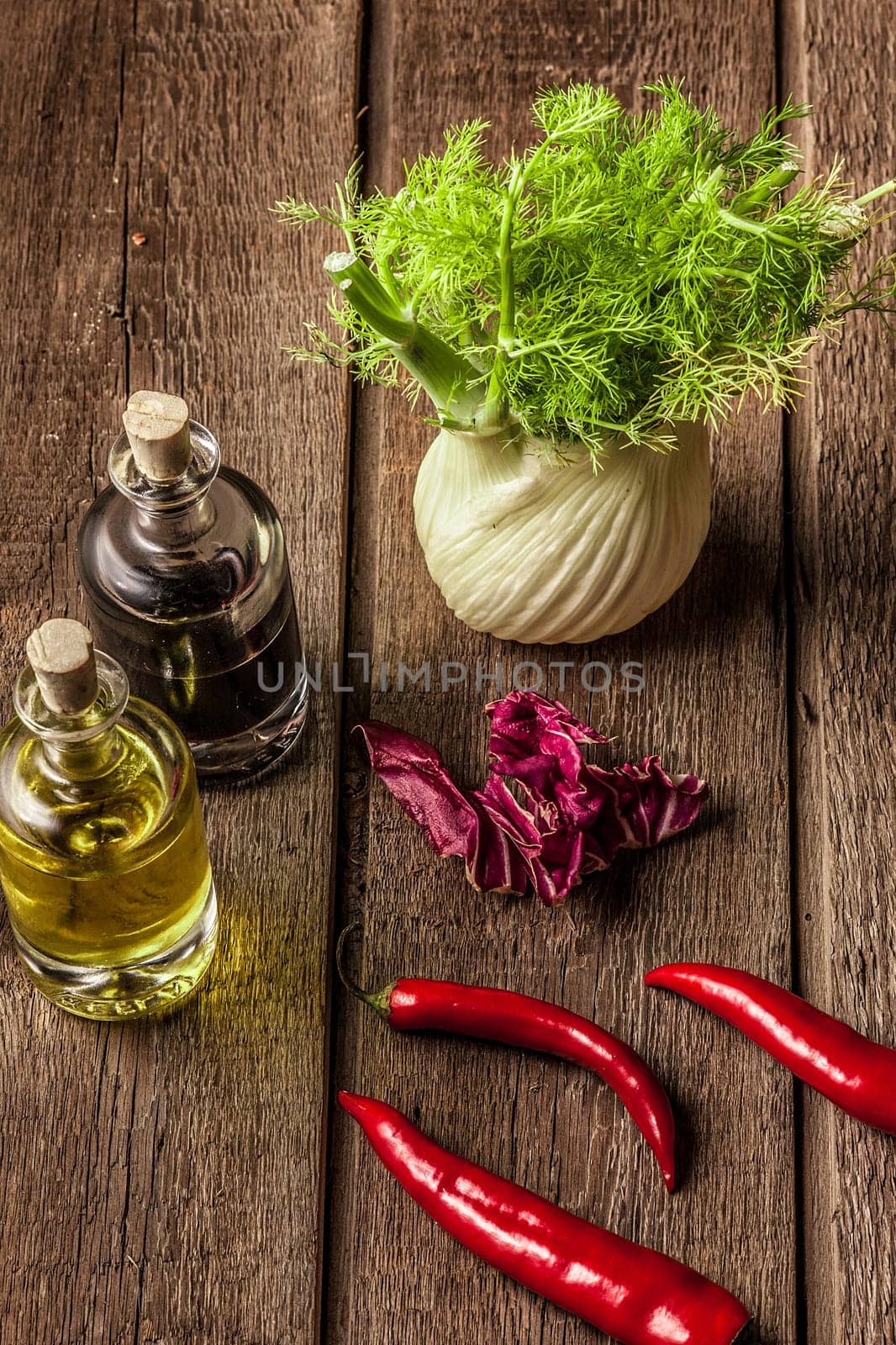 fresh fennel full of vitamins and fibers on wooden table. olive oil, balsamic vinegar, red pepper pods, bay leaves