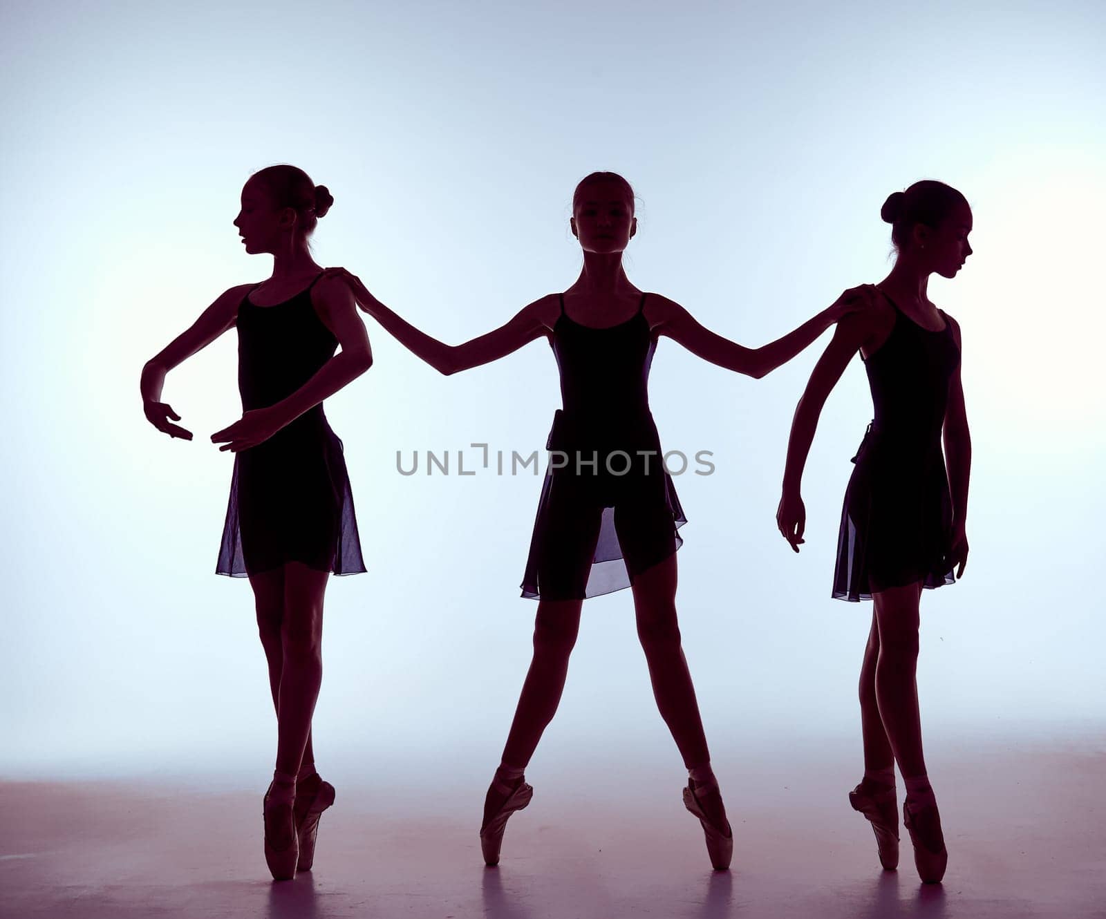 Composition from silhouettes of three young dancers in ballet poses on a gray background.  The outline shooting - silhouettes of girls.
