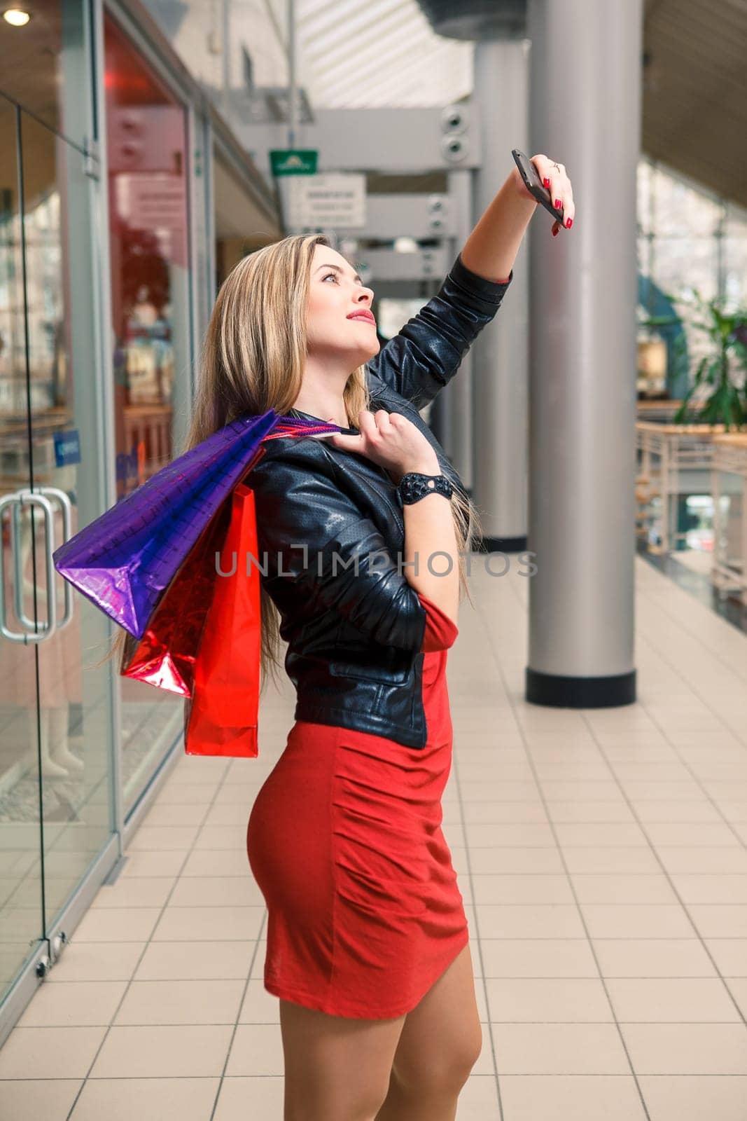 beautiful young woman goes shopping using a smartphone with a shopping bags in the mall