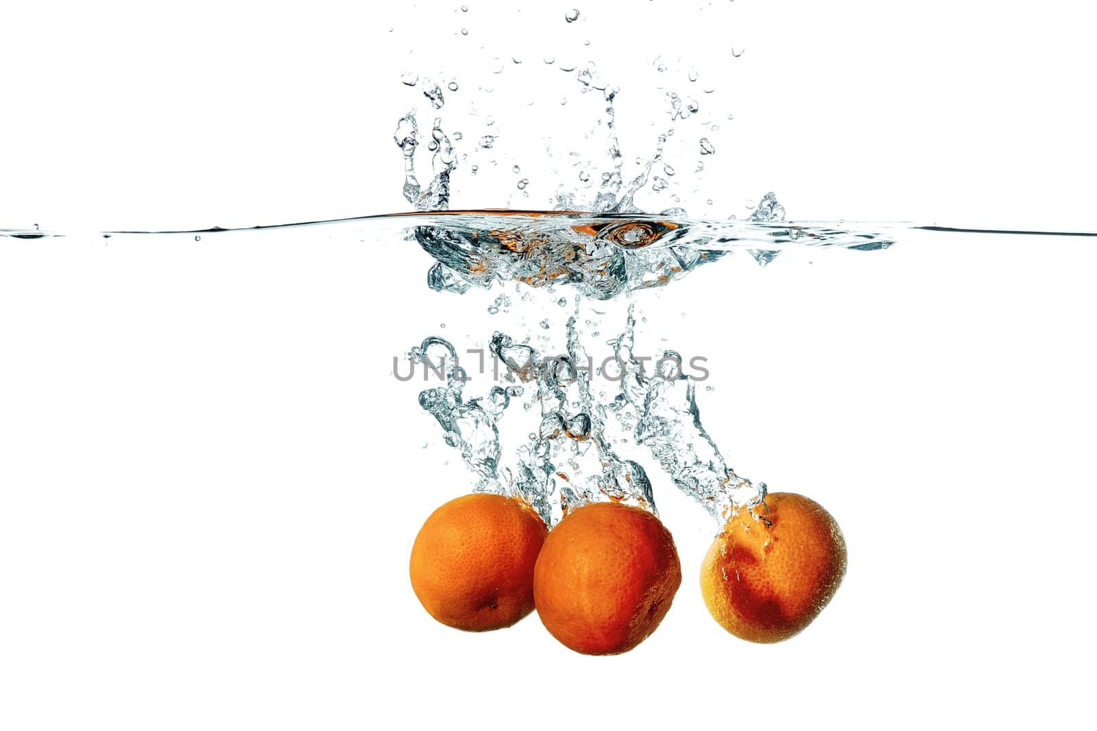 Three fresh tangerine fruits falling in water splash, isolated on white background
