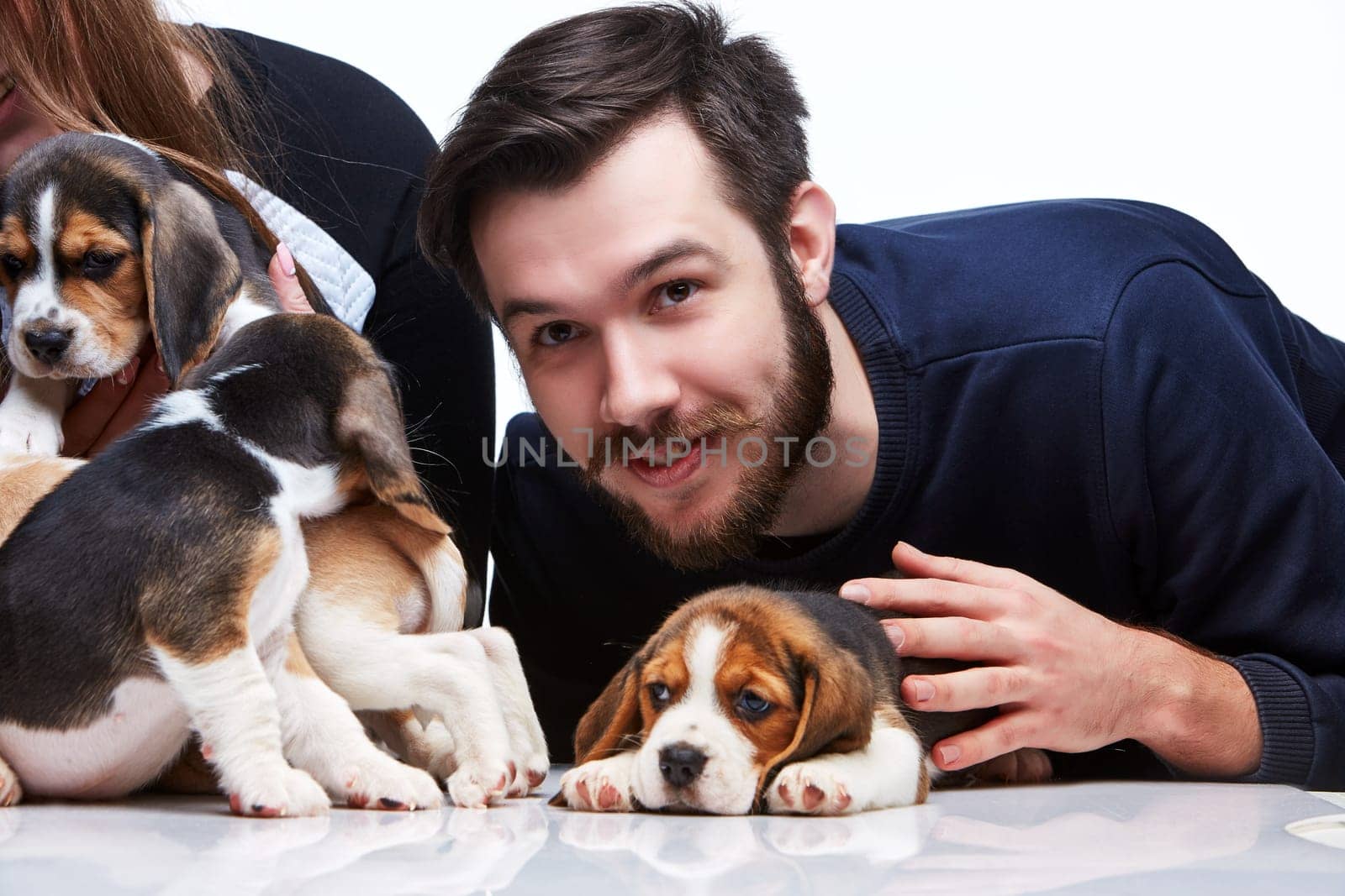 The happy man, woman and big group of a beagle puppies on white background