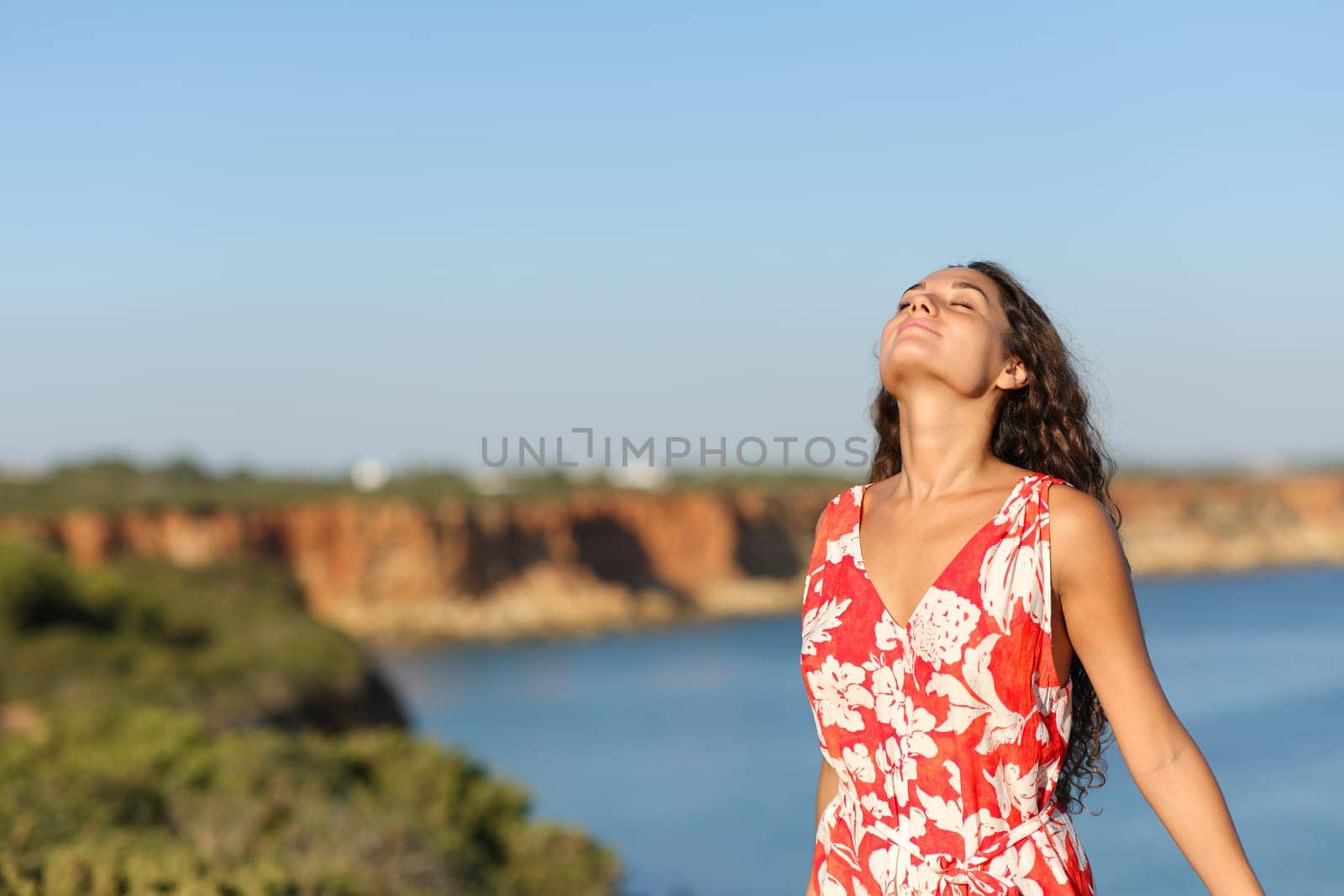 Woman in red breathing fresh air on the beach cliff