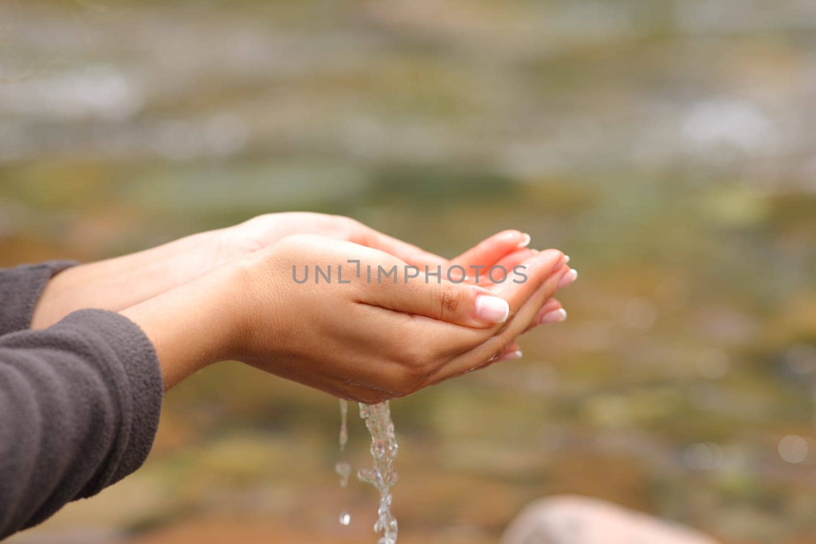 Close up of a woman hands catching fresh raw water from river