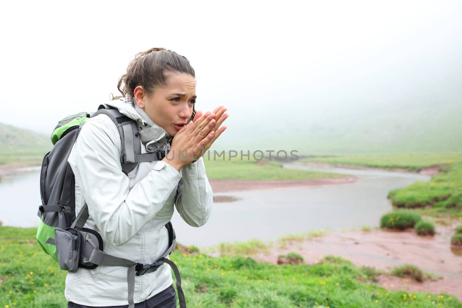 Stressed hiker getting cold walking in the mountain a foggy day