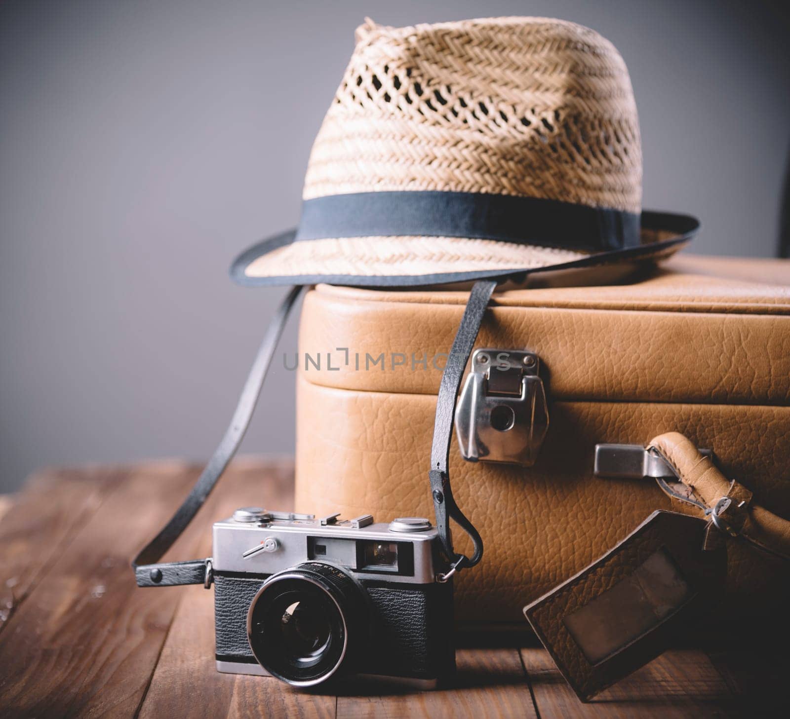 Vintage case, hipster hat, and retro camera on wooden background still life. Summer holiday vacation and adventure traveling concept with copyspace.