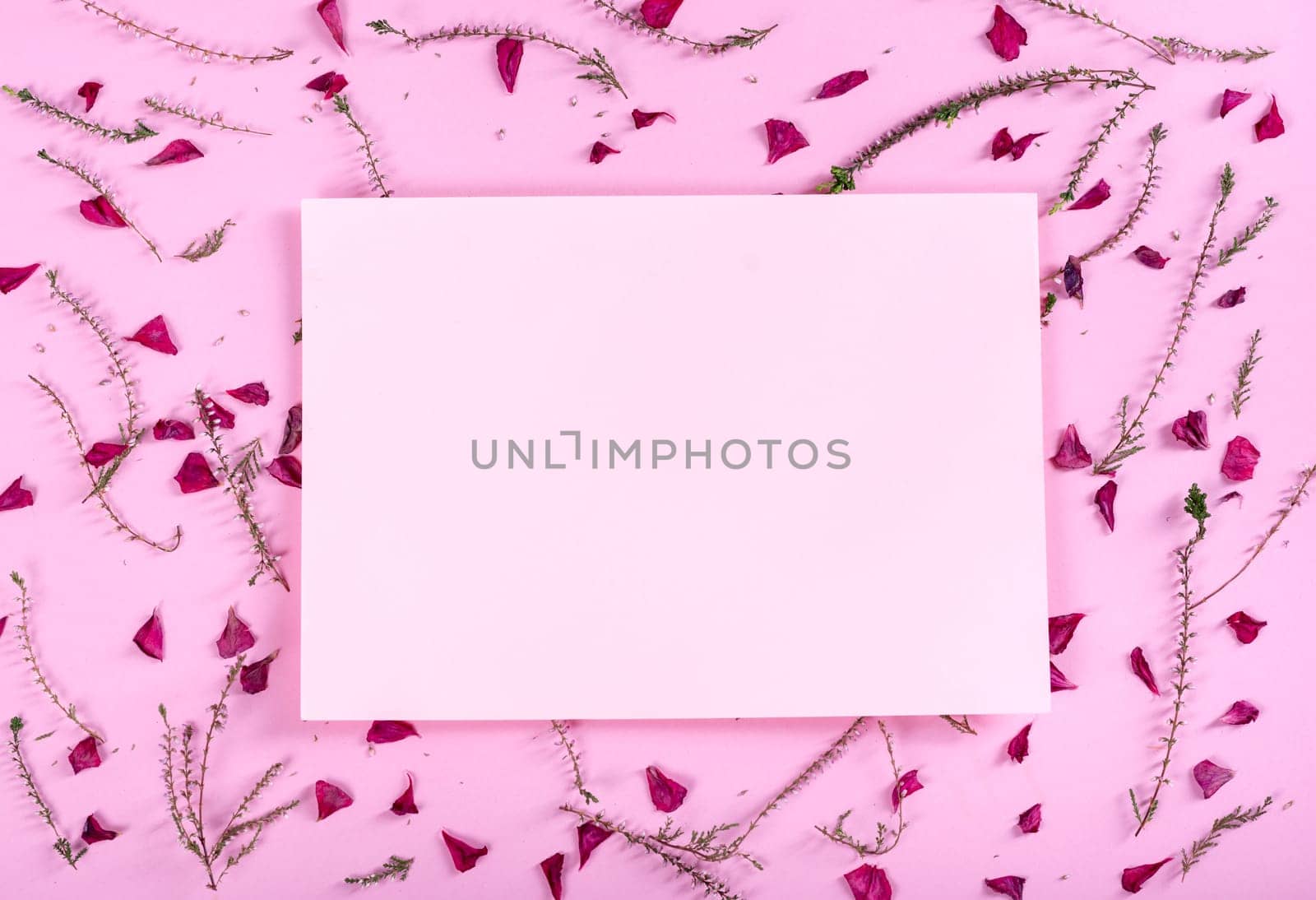 Floral pattern and empty valentine card with flowers and petals over pink background top view. Flat lay frame. Valentine's day design greeting card from above.