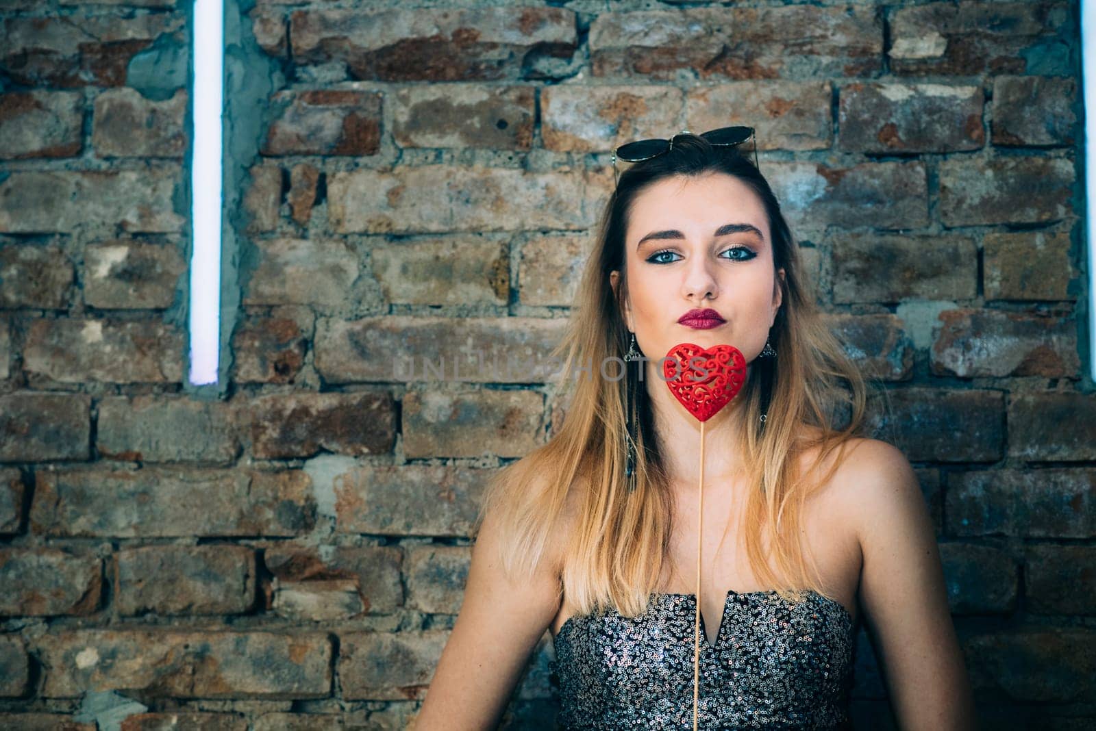 Beautiful stylish young woman holding valentine heart in in nightclub. Valentine's day party.