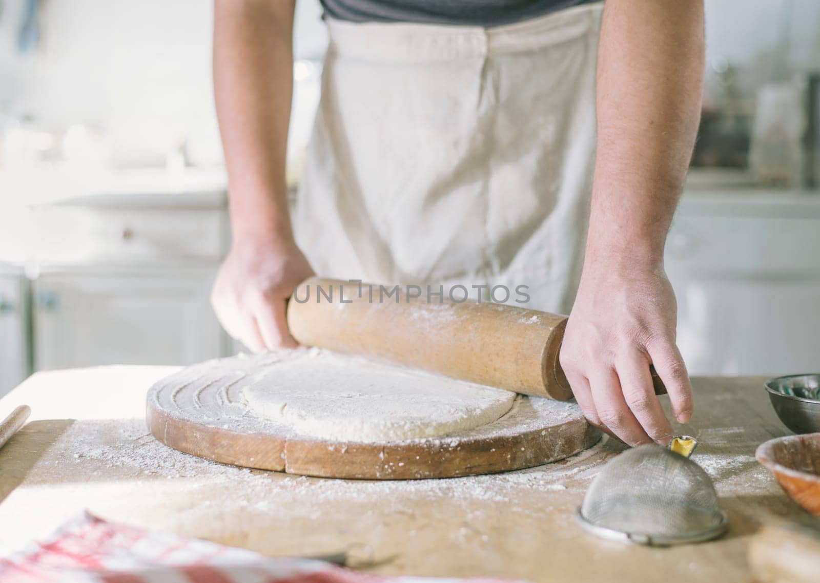 Man rolling and baking homemade dough in the kitchen. Closeup on baker's hands preparing loaf of bread. Cooking and food preparation at home.