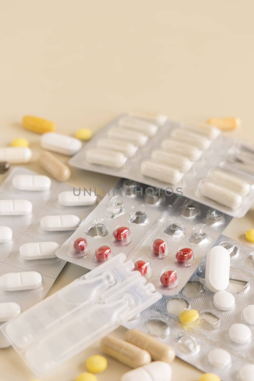 Mix of pills and capsules in a aluminum and plastic blisters with some missing pills already used on light beige close up, copy space. Preventive medicine and healthcare, dietary supplements