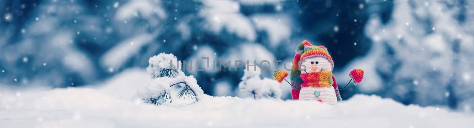 Little knitted snowman on the white snow on blue background. Beautiful panoramic view.