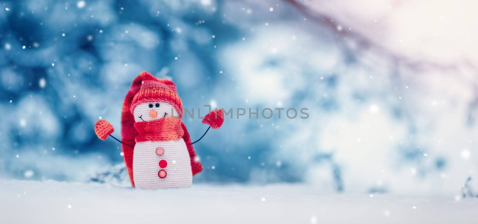 Little knitted snowman on the white snow on blue background. Beautiful panoramic view.