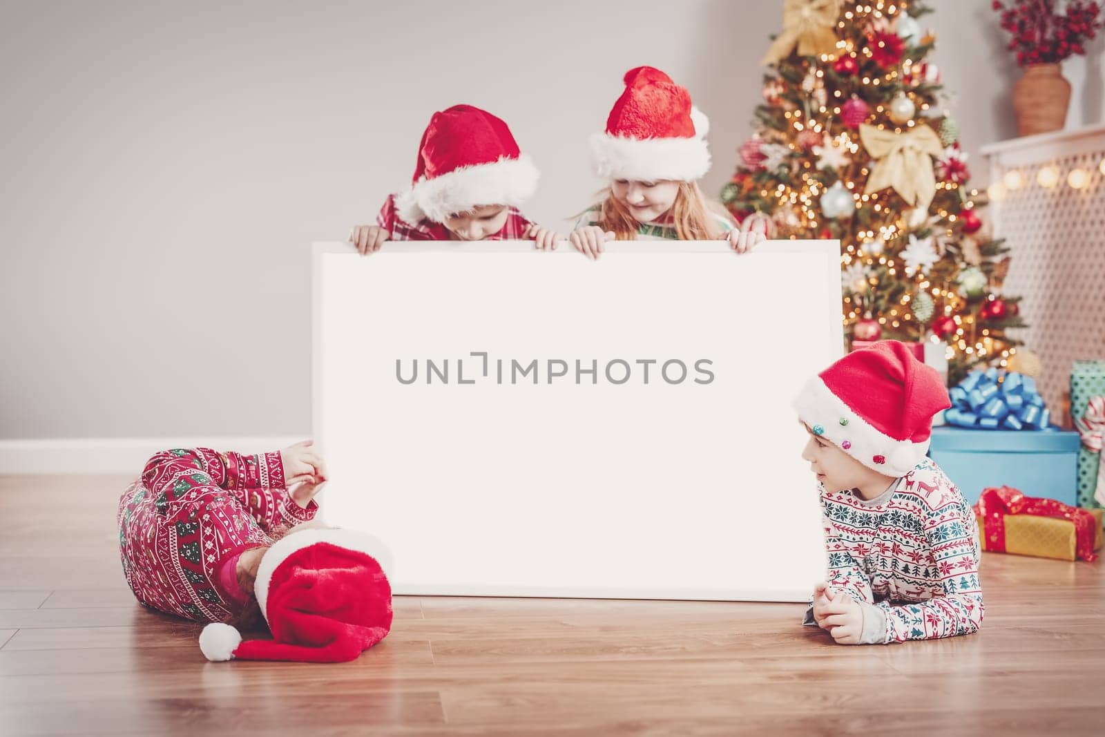 Four children indoors with empty banner on Christmas holiday. Concept of postcard, banner and info.