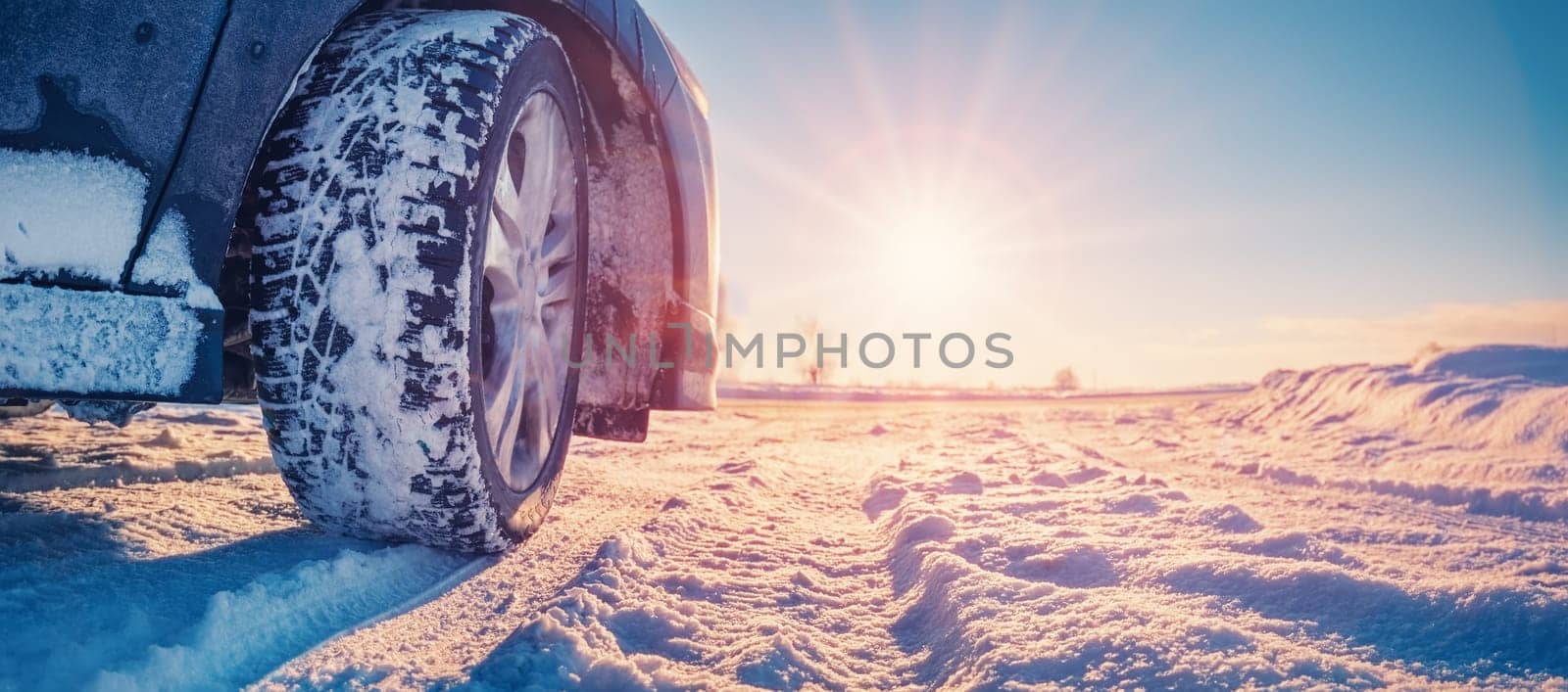 Closeup view of the car's wheel on the snowy road in natural park. Beautiful panoramic view.