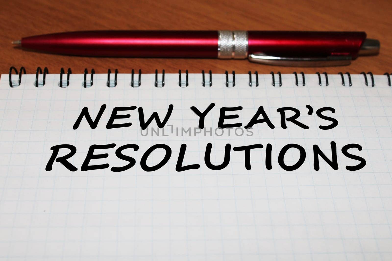 Notepad with a pen on a wooden table. View from above. The concept of resolutions for the new year.
