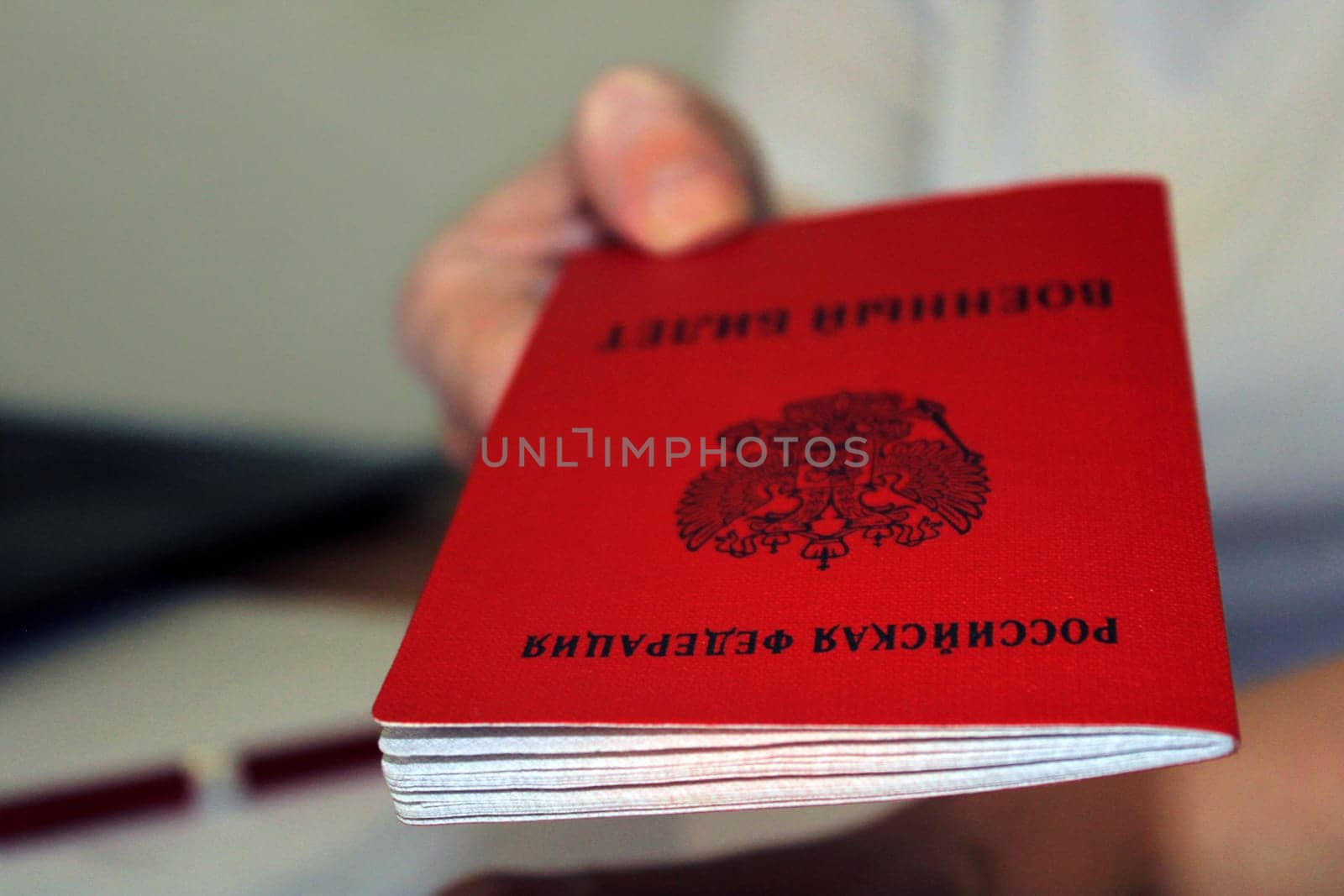 The girl holds out a military ID issued by the Russian Federation. Close-up. Blurred background. The concept of mobilization.