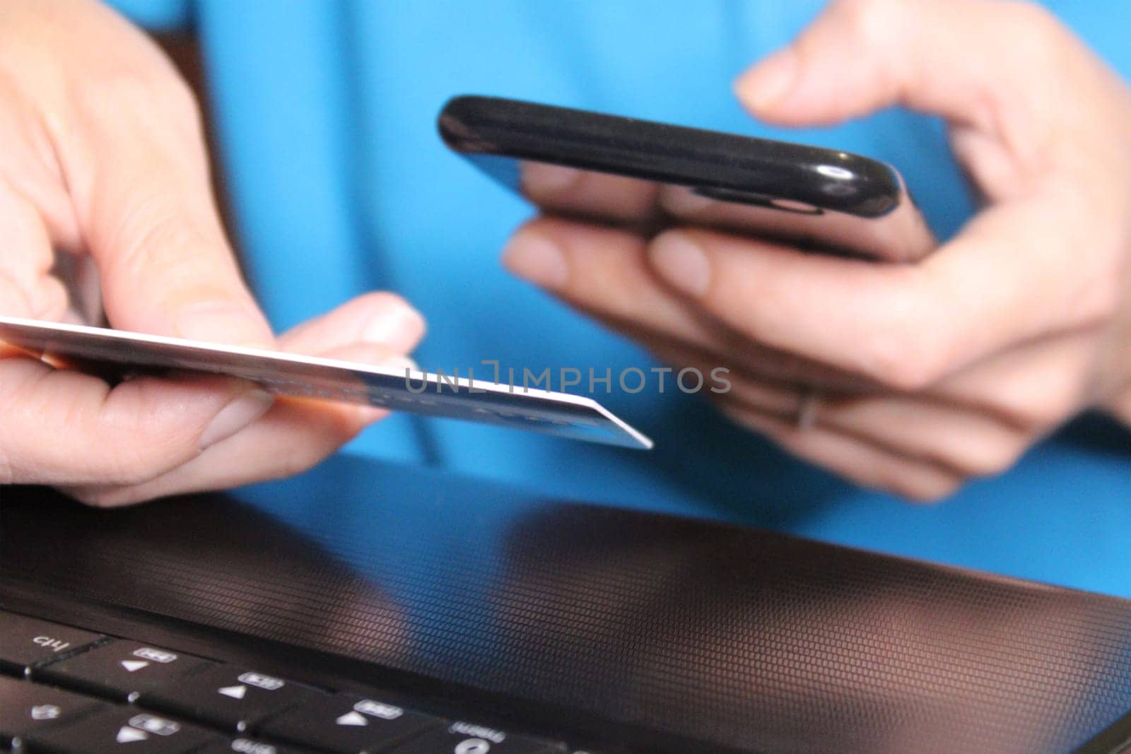 The girl sits at a laptop and holds a smartphone in her hands. Business concept. Online Shopping