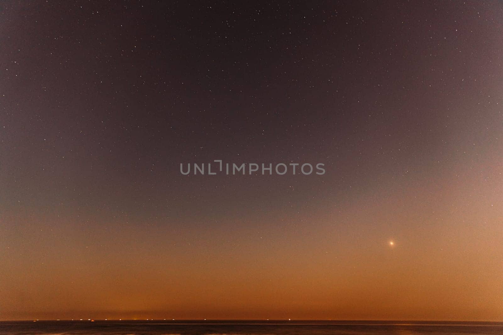 Real Colorful Night Sunset Sky Stars. Natural Starry Sky Above Sea Seascape Ocean Beach. Background.