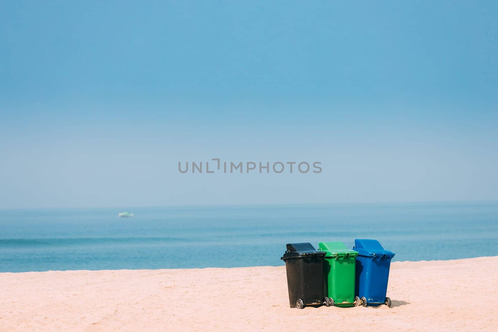 Three Colorful Plastic Waste Containers On Wheels For Separate Collection Of Garbage. Containers For Temporarily Storing Waste. Dustbins, Garbage Cans, Trash Cans On Sea Ocean Coast Beach.