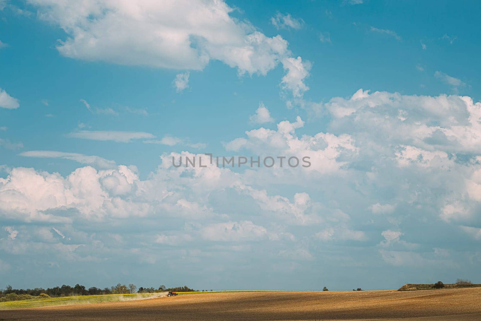 Tractor Plowing Field In Spring Season. Beginning Of Agricultural Spring Season. Cultivator Pulled By A Tractor In Countryside Rural Field Landscape.
