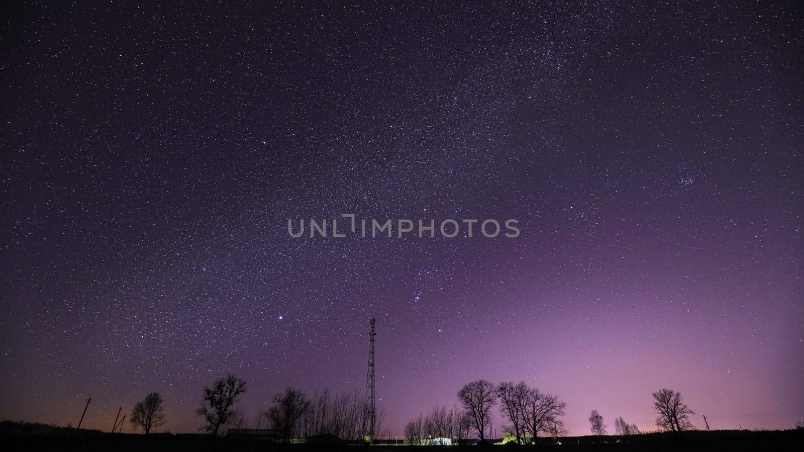 Real Night Sky Stars Above Landscape With Telecommunications Cell Phone Tower Or  With Antenna. Natural Starry Sky With Milky Way Galaxy Above Rural Countryside Landscape In Belarus.