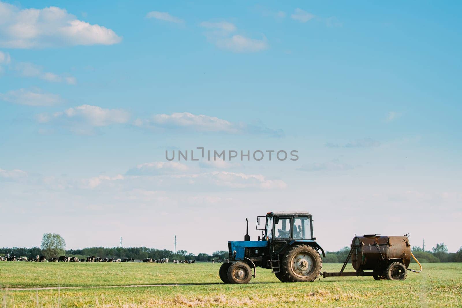Old Tractor With Tank Rides On Countryside Road. Beginning Of Agricultural Spring Season.