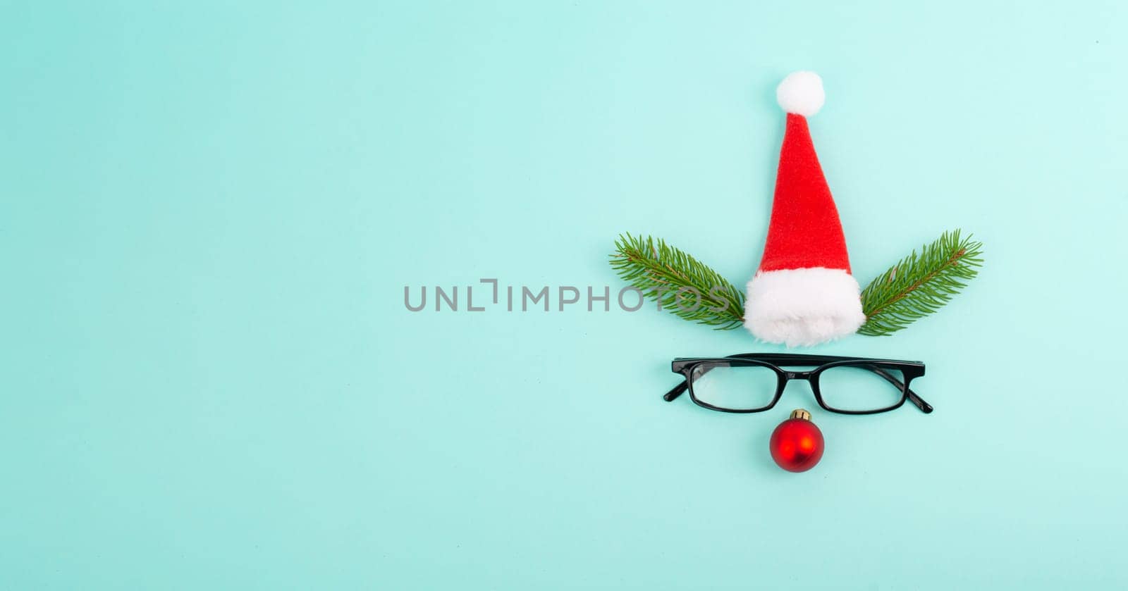 Face of a reindeer with a red bauble nose, fir antlers, a santa claus hat and eyeglasses, merry christmas greeting card