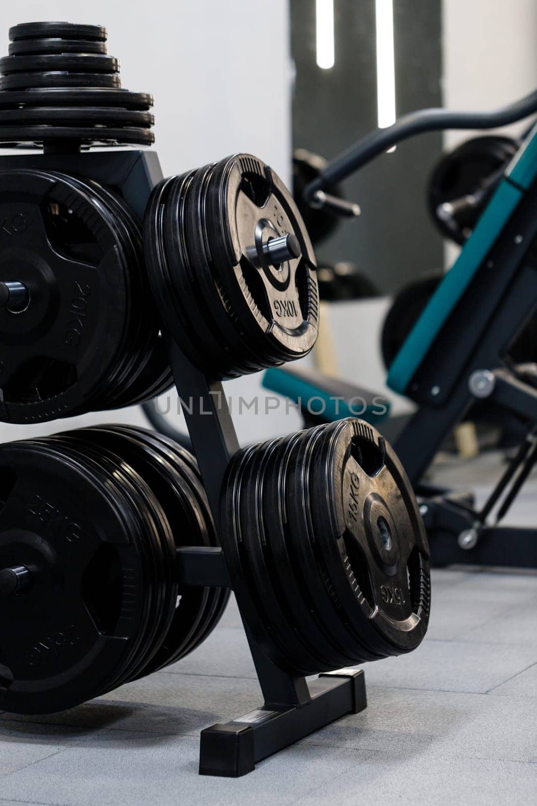 Modern disks for barbell in gym. Black metal weight plates for barbell are located on rack in sports complex. Gym equipment concept. Close up.