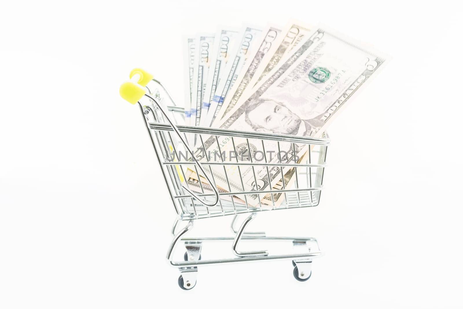 Miniature shopping cart with US dollars isolated over white background