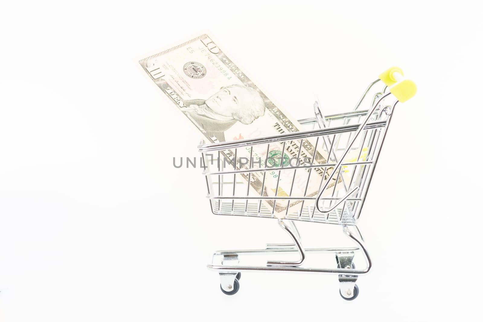 Miniature shopping cart with US dollars isolated over white background