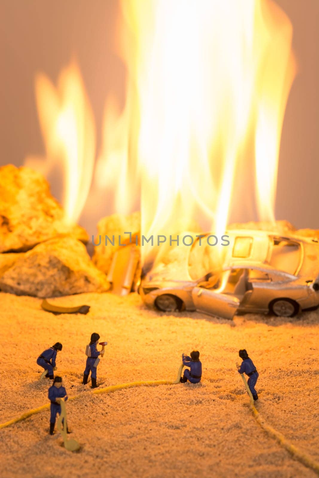 Miniature firefighters at a car accident scene in flames
