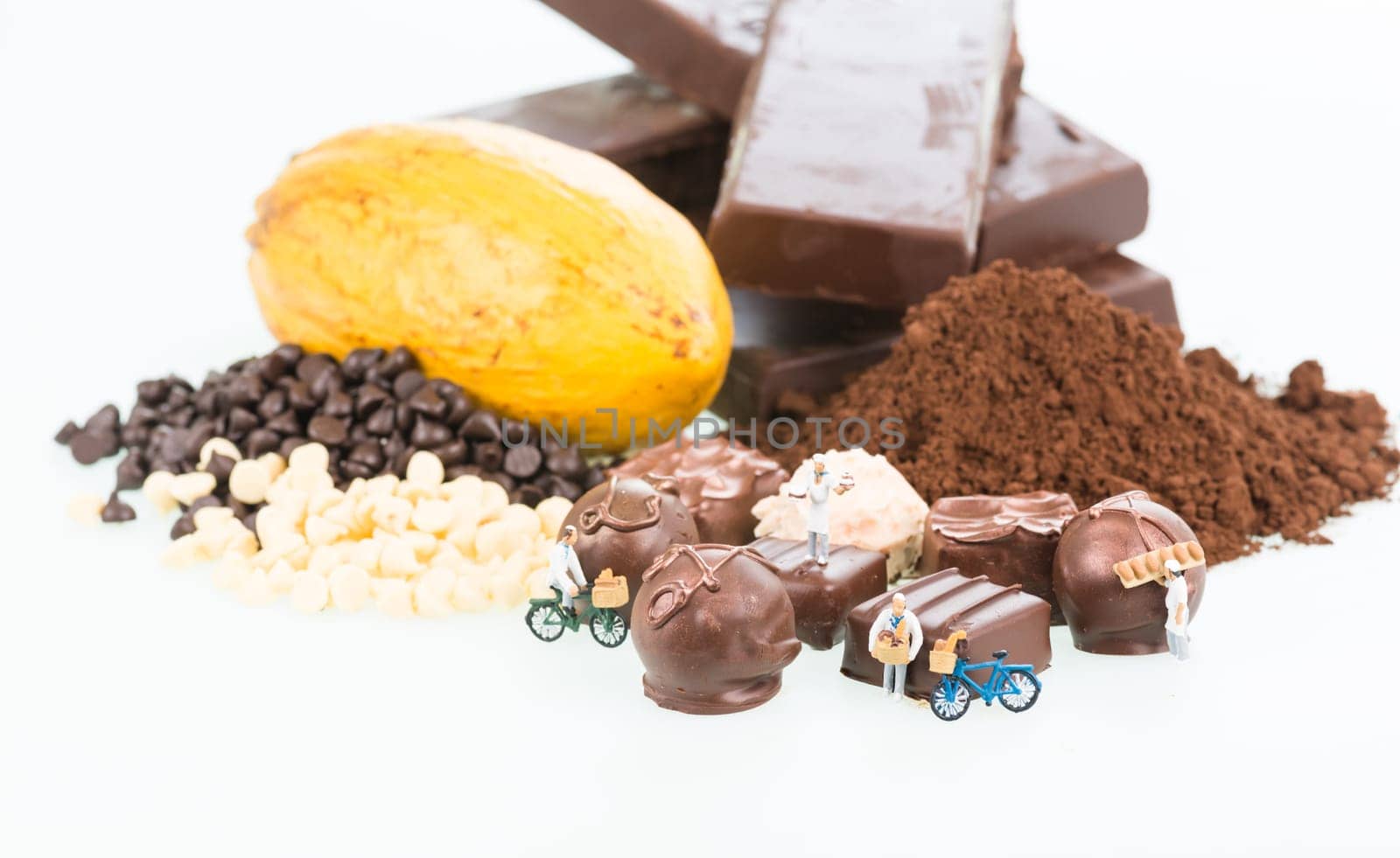 Miniature chefs and cocoa ingredients over white background