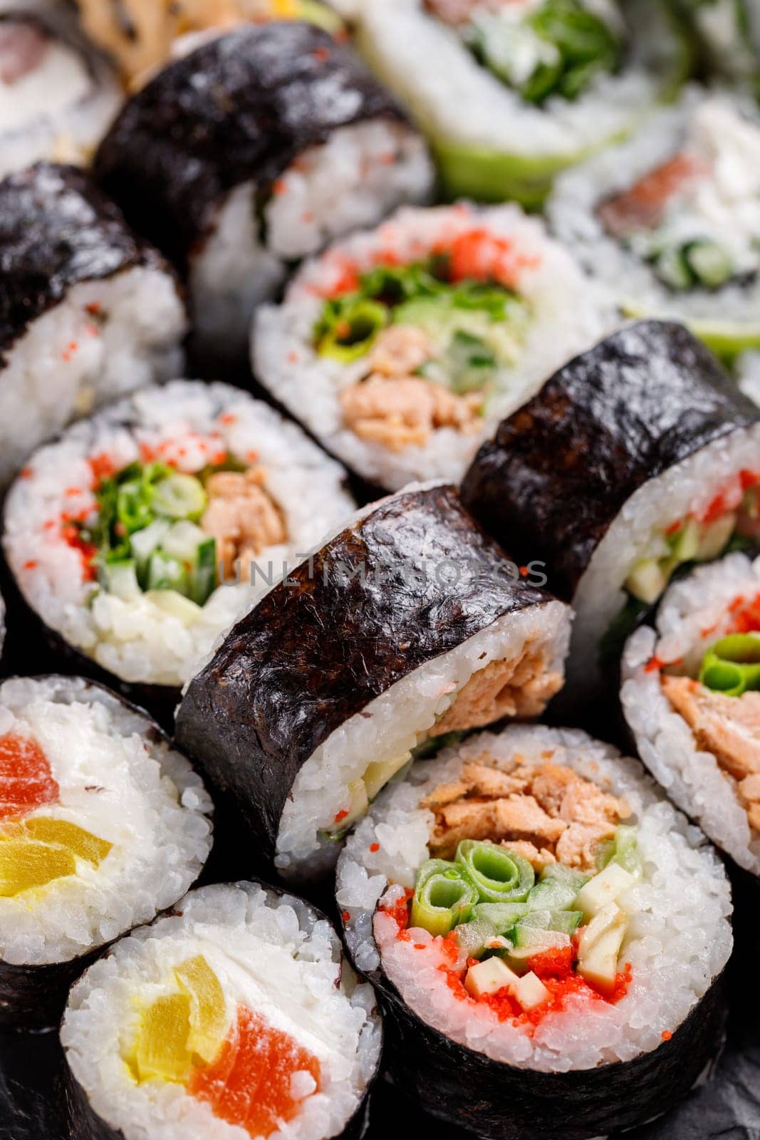 Oriental traditional seafood. Close up of original sushi rolls with different fillings standing and lying close to each other. Macro view of sushi set with different ingredients inside.