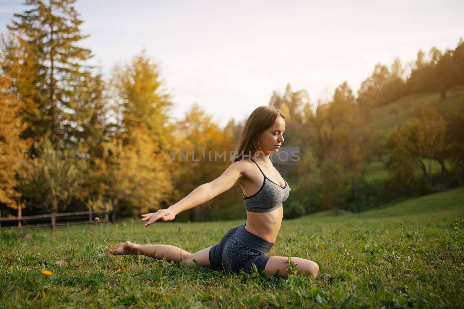 Yoga outdoor. Woman practices yoga exercises, meditation and stretching on the grass among the mountain autumn nature. Concept of healthy lifestyle and relaxation.