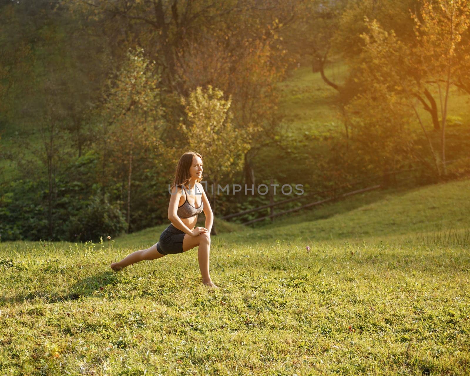 Yoga outdoor. Happy athletic woman with outstretched arms practicing breathing exercises and yoga standing barefoot on the grass. Yoga as a daily morning ritual.