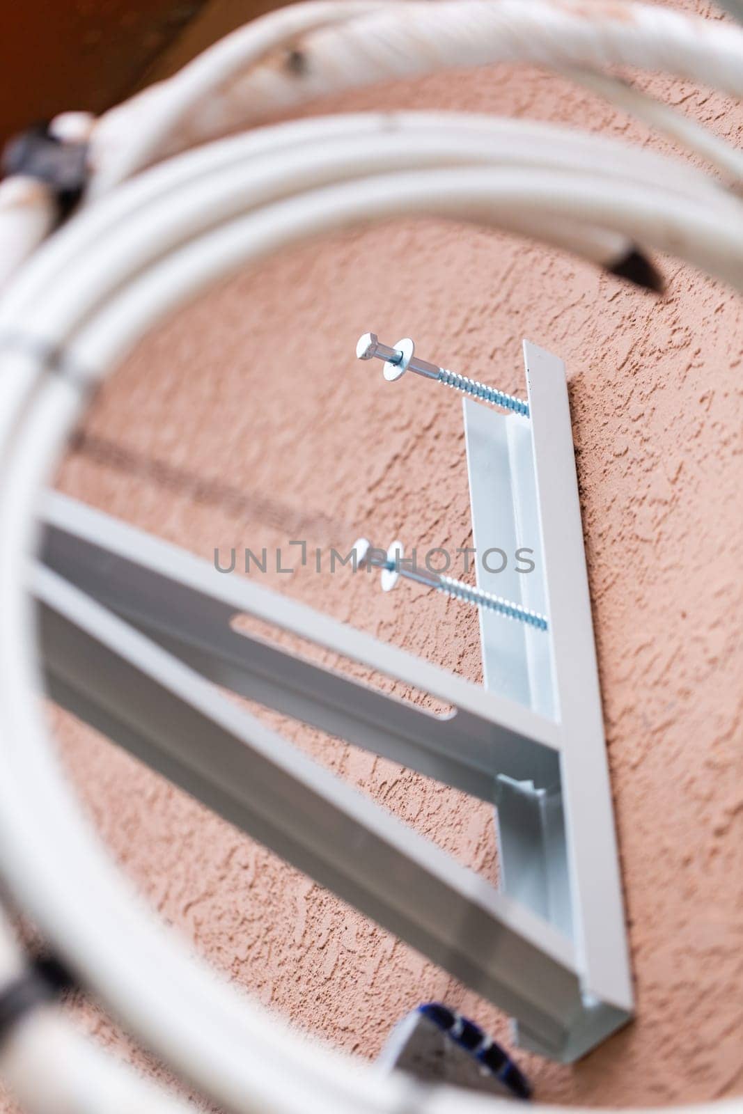 Unscrewed screws on metal holder of wall air conditioner. Close up of mounting parts for outdoor air conditioner unit. Concept of installing air conditioning system.
