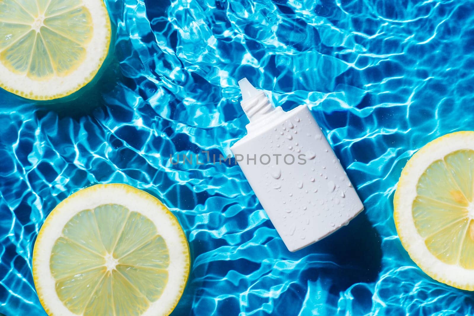 White beauty product sunscreen cream vial tube bottle in transparent fresh exhilarant wave water with flecks, lemon citrus slices. Body skin care protection in summer beach travel concept. Flat lay.