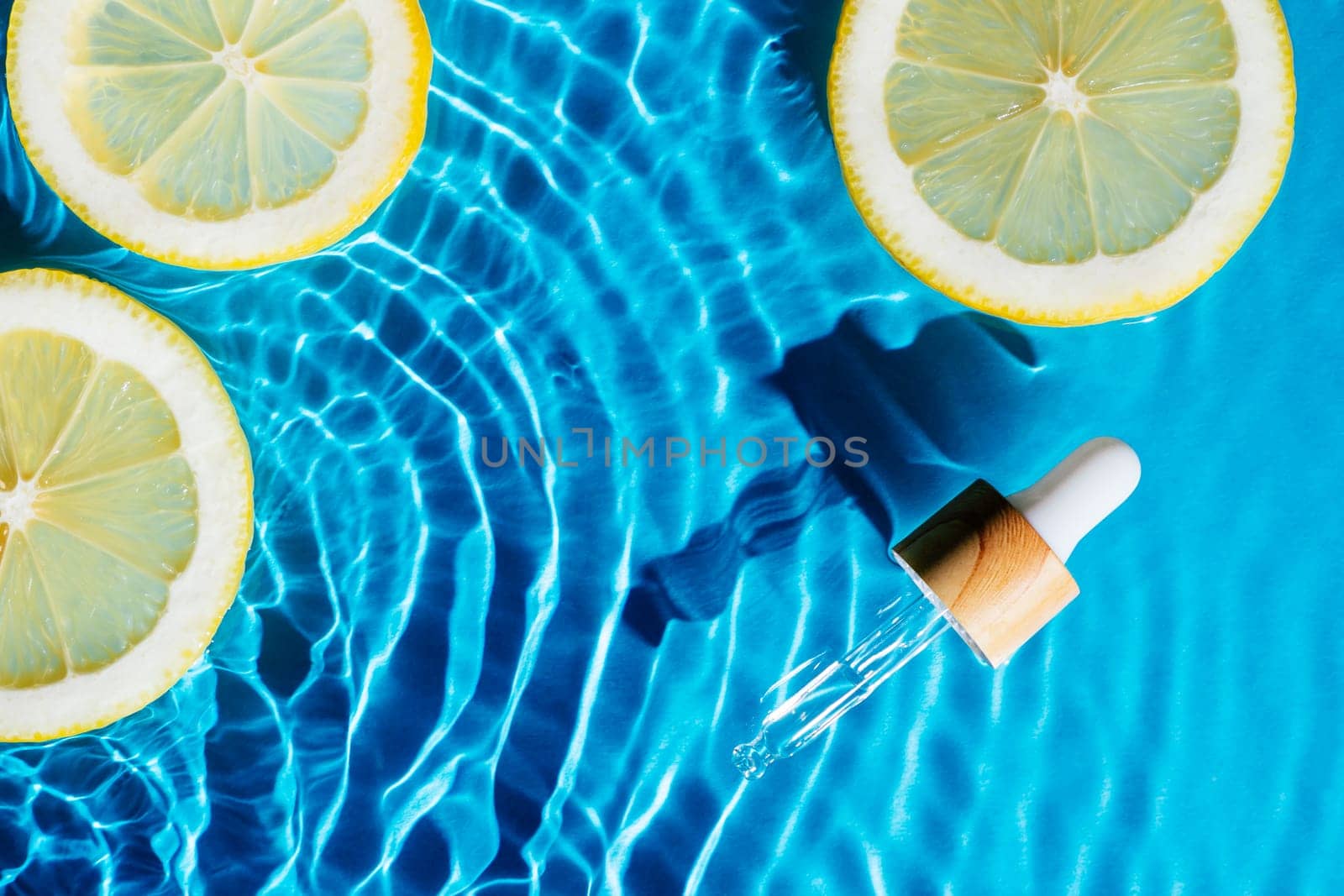 Facial pipette serum, whey beauty product near fruit citrus lemon in water splashing fresh transparent, flecks. Flat lay, top view. Summer beach tropical. Organic skin body antiage care in hot climate