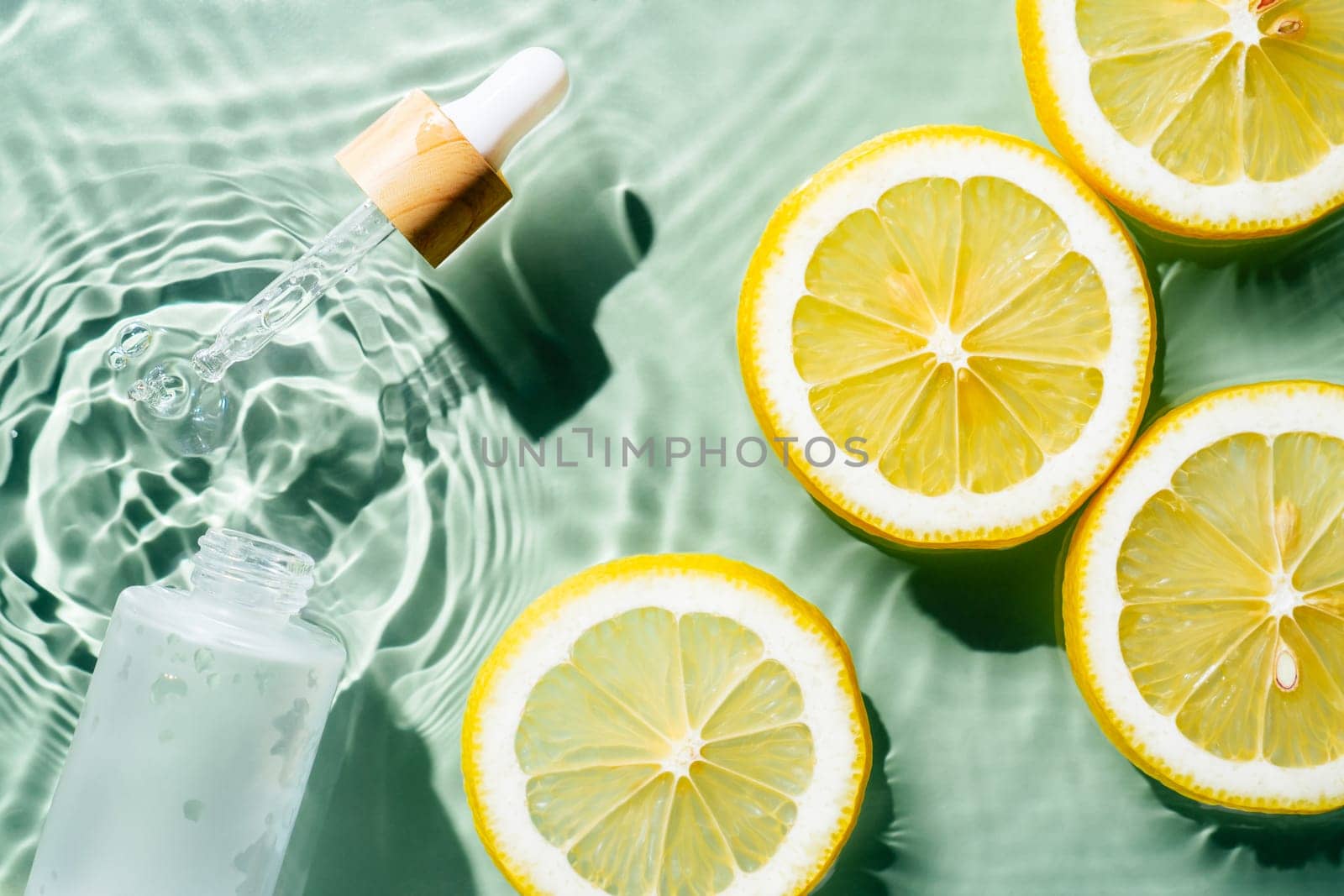 Facial pipette serum, whey beauty product near fruit citrus lemon in water splashing fresh transparent, flecks. Flat lay, top view. Summer beach tropical. Organic skin body antiage care in hot climate