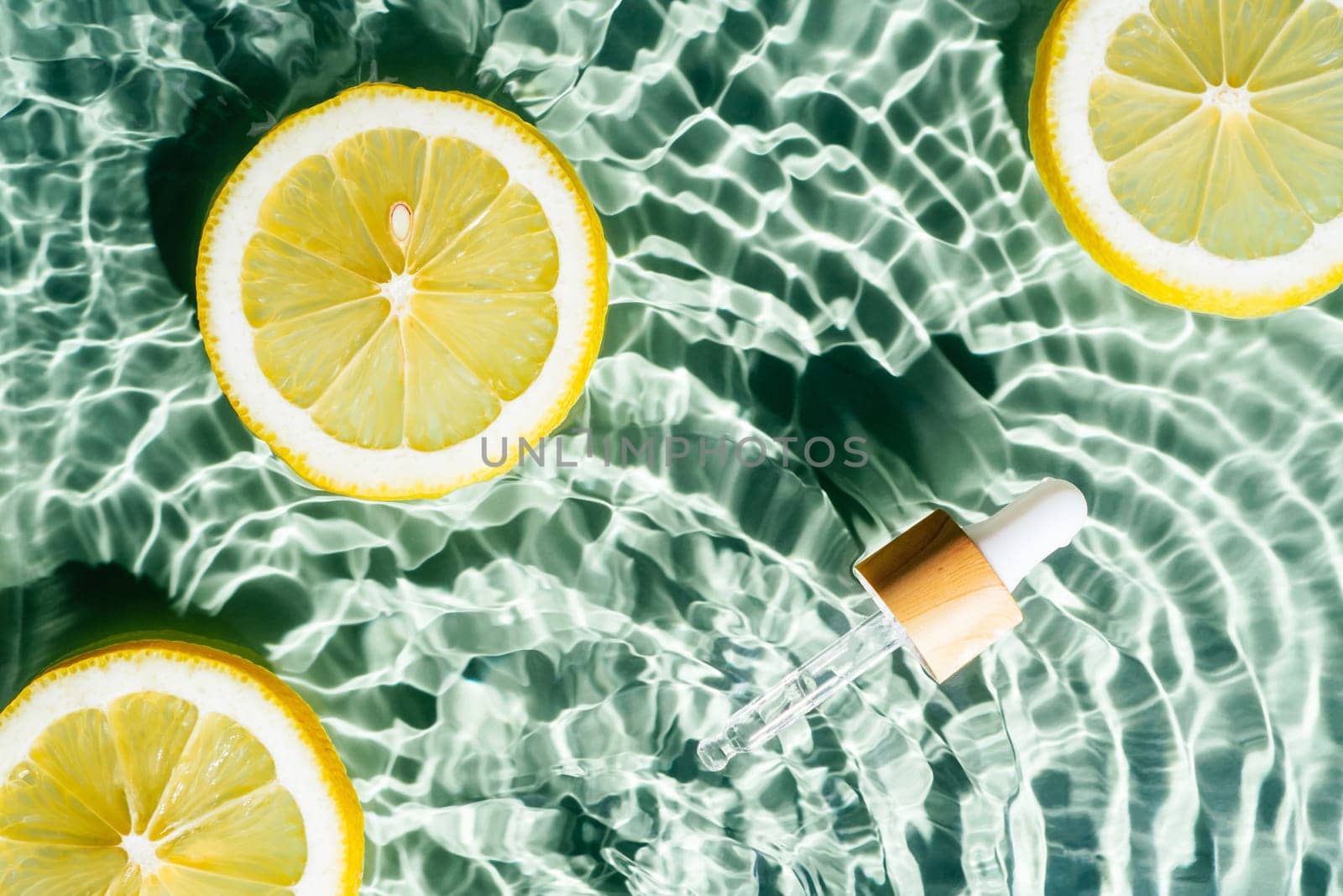 Facial pipette serum, whey beauty product near fruit citrus lemon in water splashing fresh transparent, flecks. Flat lay, top view. Summer beach tropical. Organic skin body antiage care in hot climate