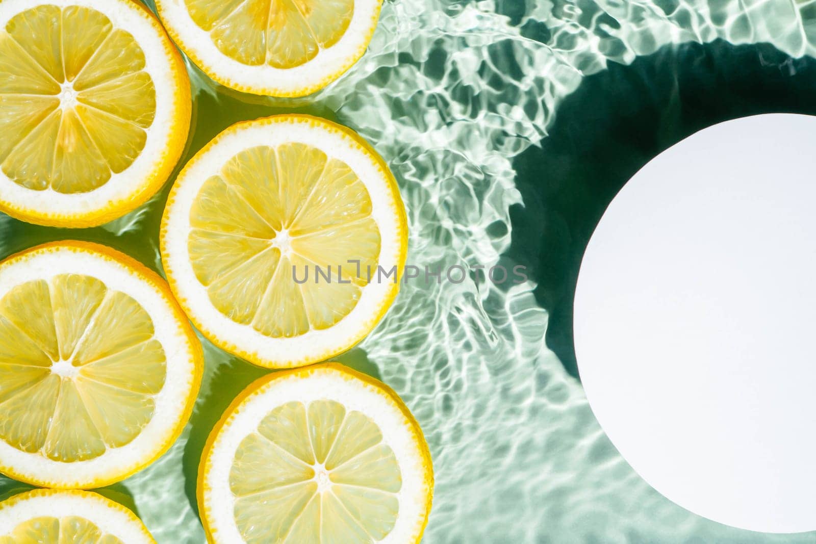 White circle copy space in transparent fresh exhilarant wave water with flecks background, lemon citrus slices. Summer freshness, healthy eating beach travel drinks concept. Flat lay, copy space