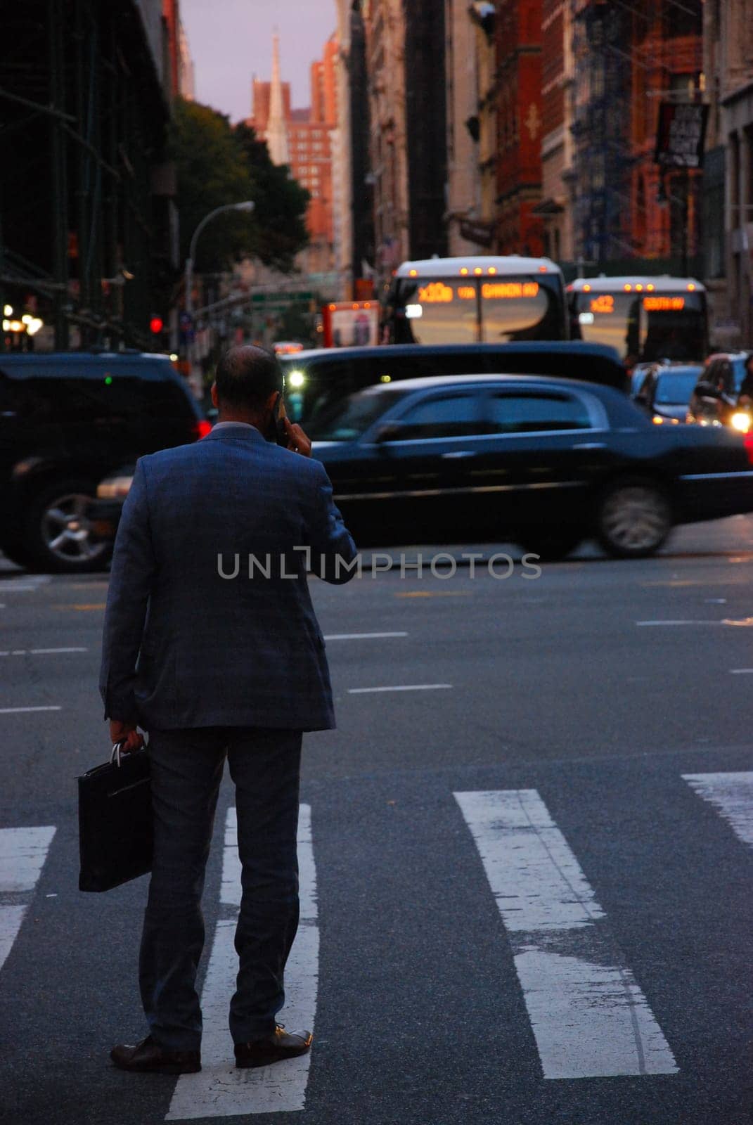 Back shot of businessman in New York in suit talking on cell phone on the streets of New York City, US