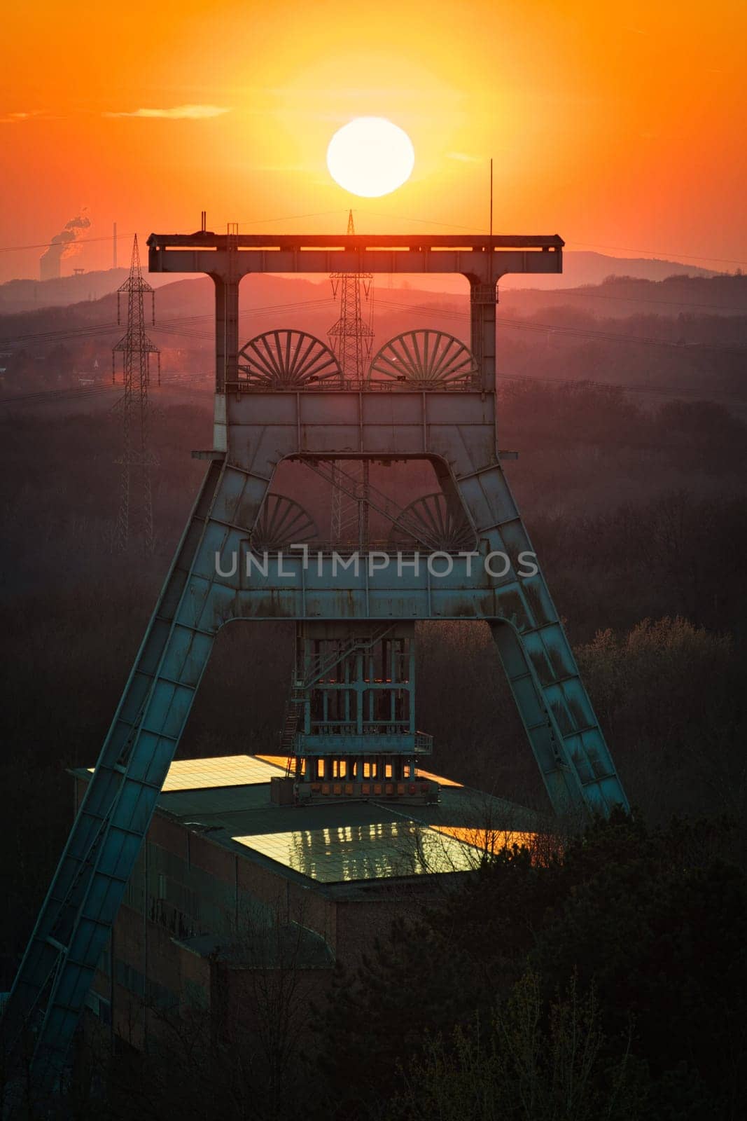 Vertical shot of a headframe tower with a golden sun setting in the background in Herten, Germany