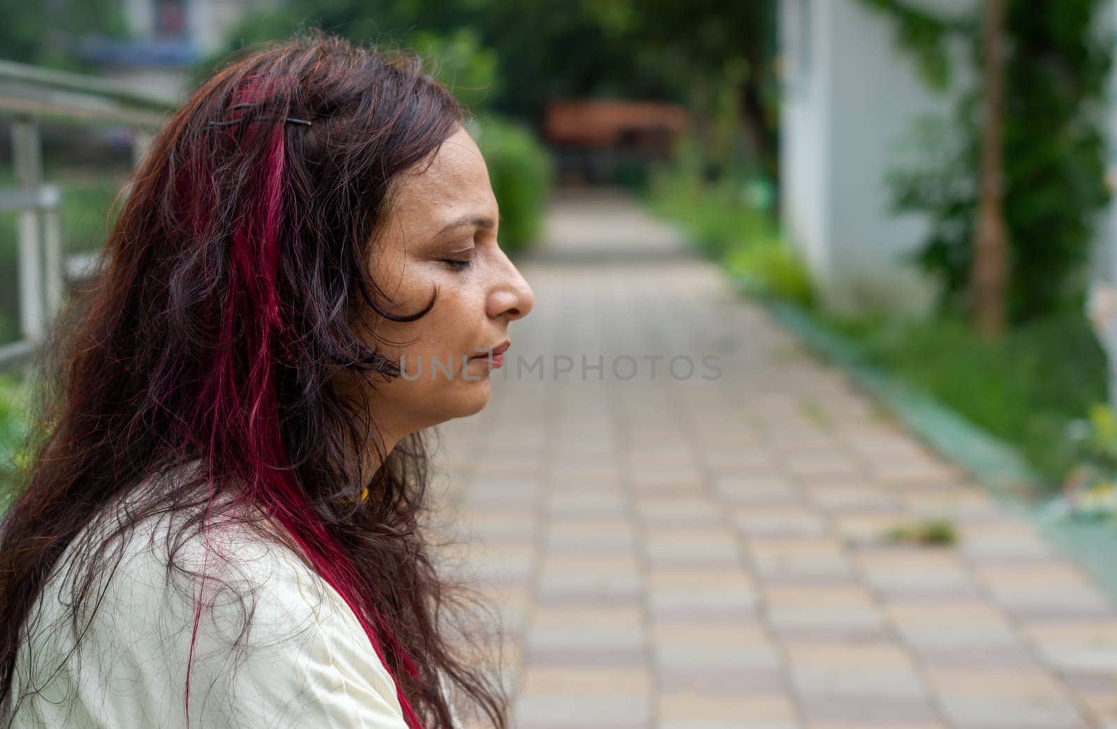 Senior Woman in meditation sitting with eyes closed concentrate in a public park. Side view. Medium Shot. Close up portrait.