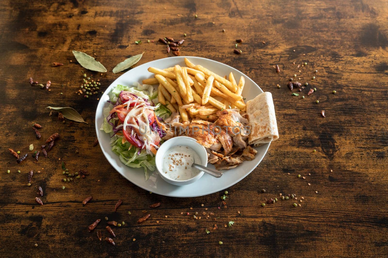 Kebab plate with french frizes and white sauce on a wooden table