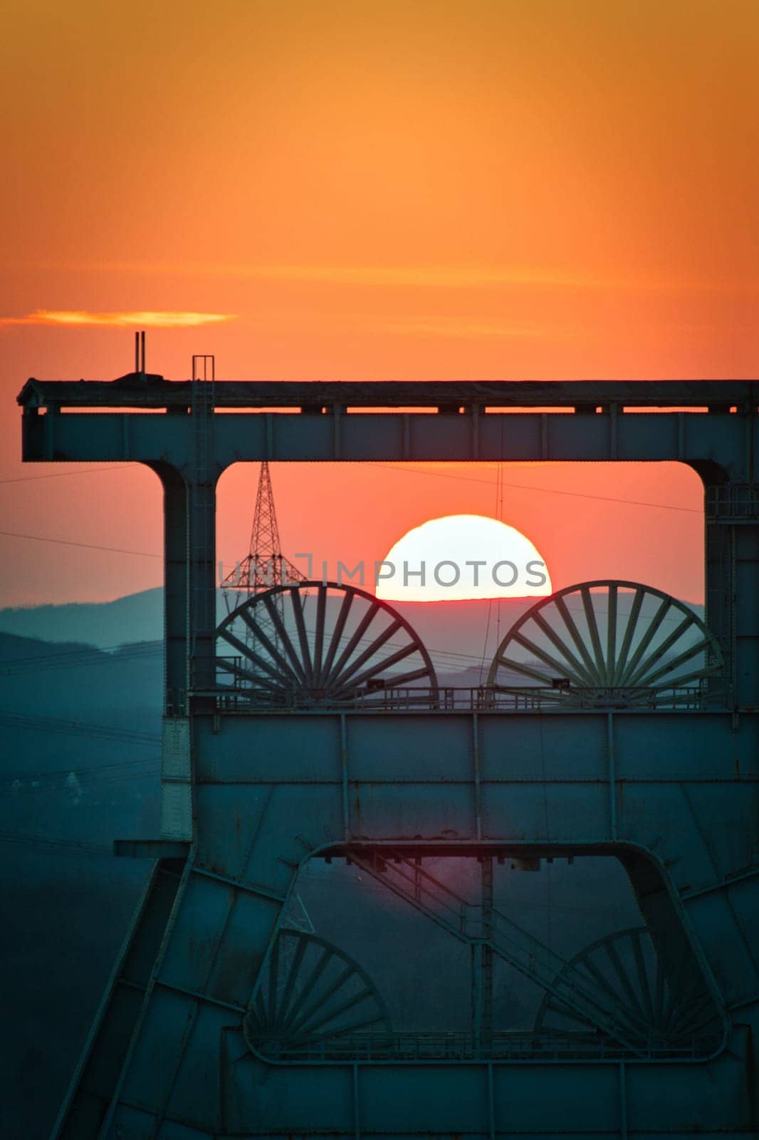 Vertical shot of a headframe tower with a golden sun setting in the background in Herten, Germany