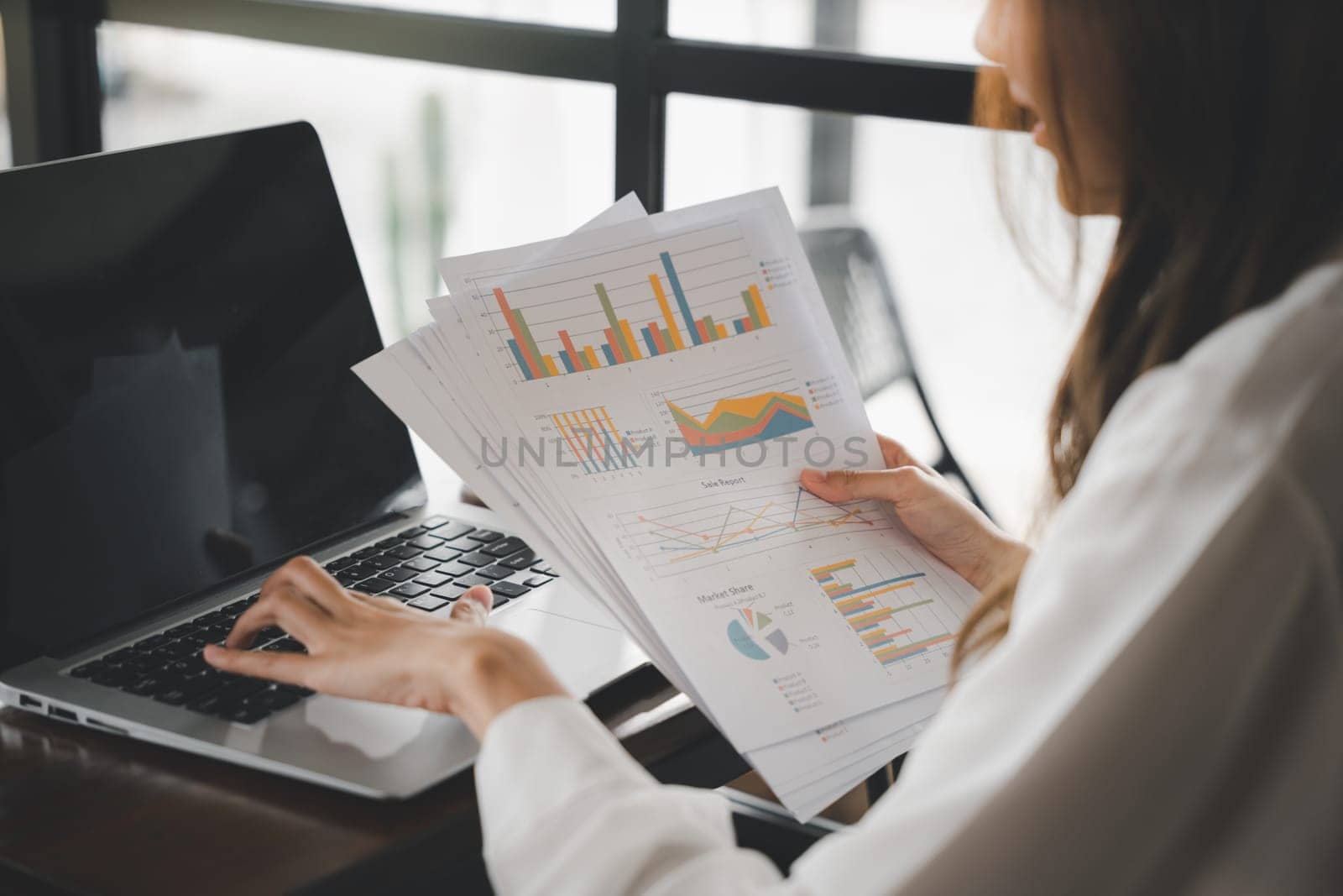 Businesswoman working and comparing forecasting and graphic documents paperwork with laptop computer, Happy female holding papers review report analyzing work results on graph chart outside office