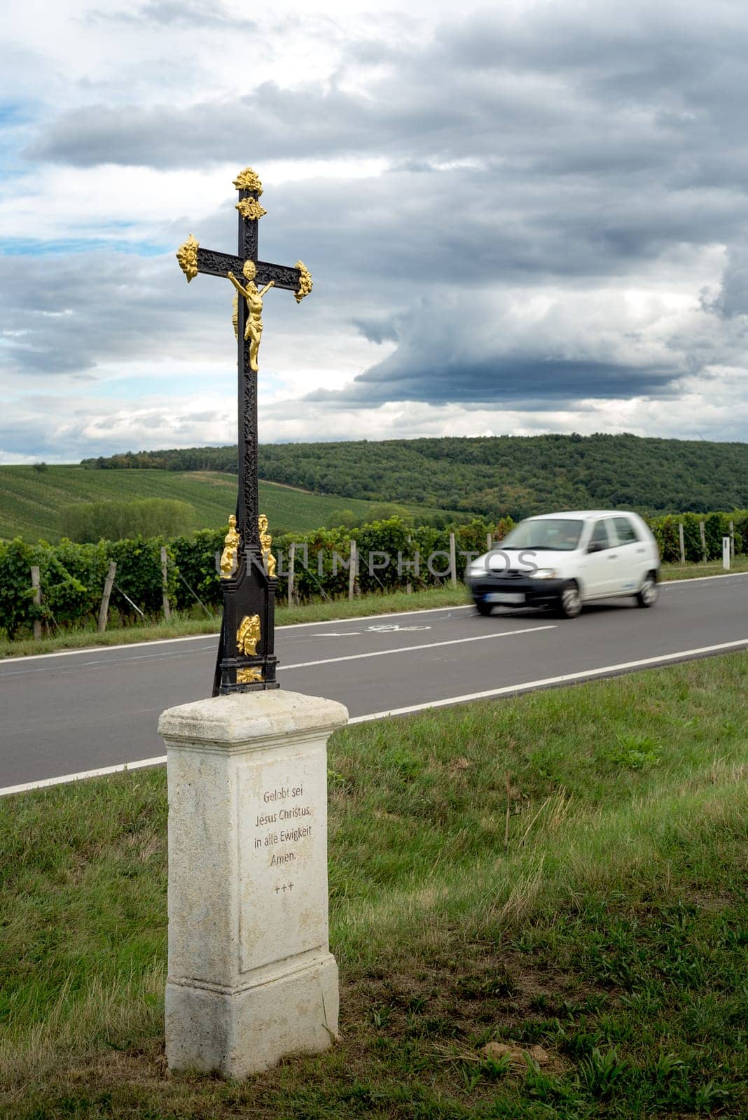 religious cross near a road with car