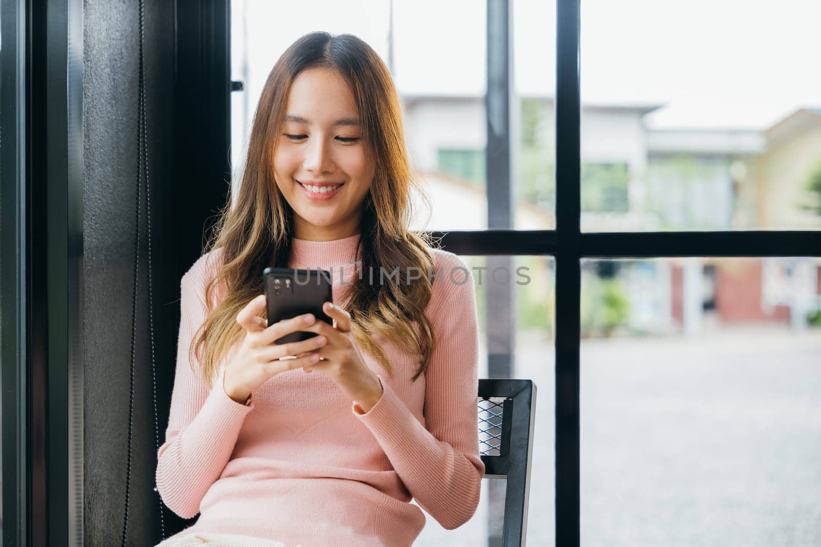 Happy beautiful female typing text message on smart phone device and enjoyment lifestyle with social networking media, Asian young woman using mobile phone at cafe coffee shop to shopping online